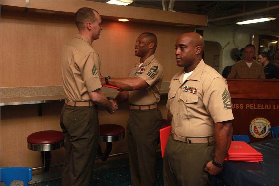 Corporal Paul A. Riley, combat engineer, Combat Logistics Battalion 15, 15th Marine Expeditionary Unit, receives his graduation certificate from Sgt. Maj. John W. Scott, the 15th MEU sergeant major, on the troop mess decks of USS Peleliu during Corporals' Course graduation, March 15. Corporals' Course is a professional military education for enlisted Marines designed to give corporals the tools to become more effective small unit leaders. The 15th MEU is deployed as part of the Peleliu Amphibious Ready Group as a U.S. Central Command theater reserve force, providing support for maritime security operations and theater security cooperation efforts in the U.S. 5th Fleet area of responsibility. Riley, 27, is from Jasper, Tenn. (U.S. Marine Corps photo by Cpl. John Robbart III)