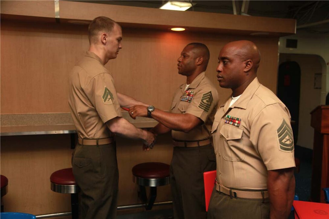 Corporal Jeremy A. Reason, AV-8B engine mechanic, Marine Medium Helicopter Squadron 364 (Rein.), 15th Marine Expeditionary Unit, receives his graduation certificate from Sgt. Maj. John W. Scott, the 15th MEU sergeant major, on the troop mess decks of USS Peleliu during Corporals' Course graduation, March 15. Corporals' Course is a professional military education for enlisted Marines designed to give corporals the tools to become more effective small unit leaders. The 15th MEU is deployed as part of the Peleliu Amphibious Ready Group as a U.S. Central Command theater reserve force, providing support for maritime security operations and theater security cooperation efforts in the U.S. 5th Fleet area of responsibility. Reason, 24, is from Washington, N.C. (U.S. Marine Corps photo by Cpl. John Robbart III)