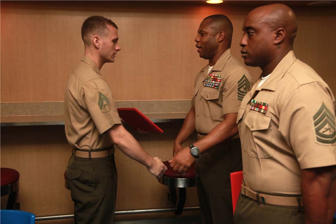 Corporal Nathan S. Sheppard, AV-8B Harrier airframes mechanic, Marine Medium Helicopter Squadron 364 (Rein.), 15th Marine Expeditionary Unit, receives his graduation certificate from Sgt. Maj. John W. Scott, the 15th MEU sergeant major, on the troop mess decks of USS Peleliu during Corporals' Course graduation, March 15. Corporals' Course is a professional military education for enlisted Marines designed to give corporals the tools to become more effective small unit leaders. The 15th MEU is deployed as part of the Peleliu Amphibious Ready Group as a U.S. Central Command theater reserve force, providing support for maritime security operations and theater security cooperation efforts in the U.S. 5th Fleet area of responsibility. Sheppard, 23, is from Gillette, Wyo. (U.S. Marine Corps photo by Cpl. John Robbart III)