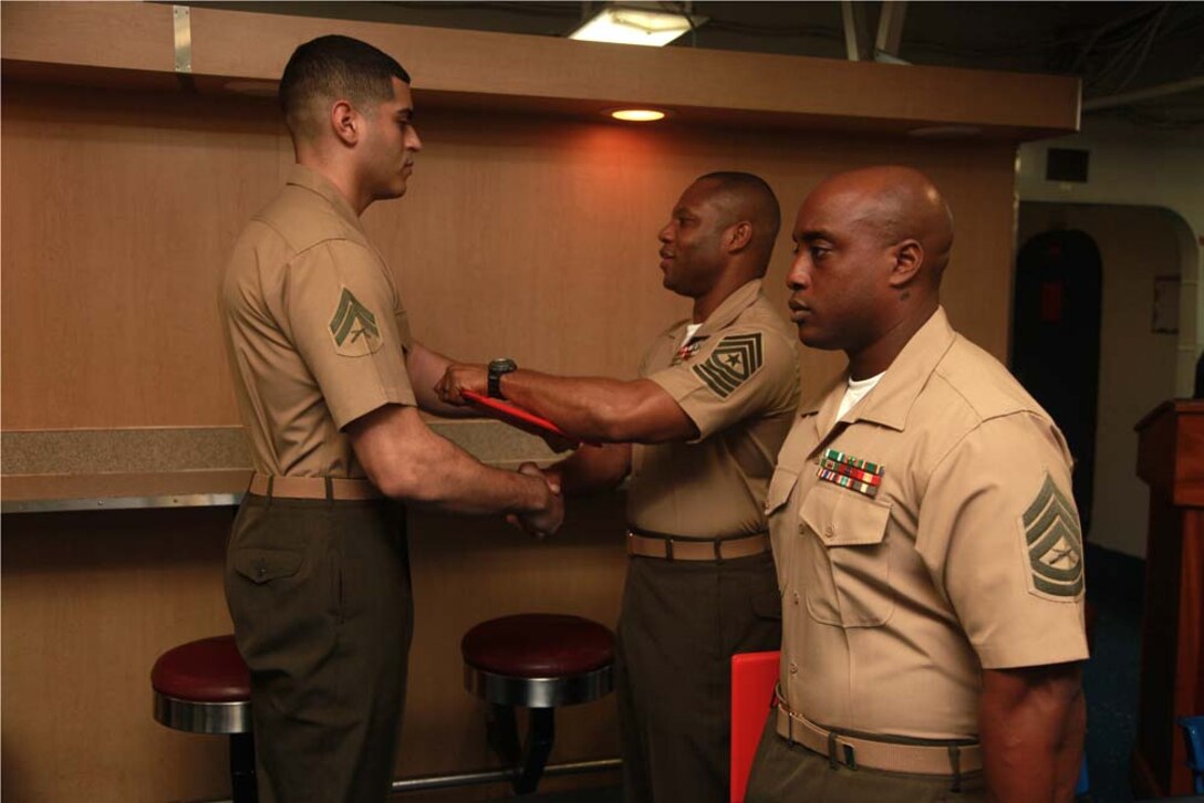 Corporal Jefferson M. Urrutia, radio operator, Command Element, 15th Marine Expeditionary Unit, receives his graduation certificate from Sgt. Maj. John W. Scott, the 15th MEU sergeant major, on the troop mess decks of USS Peleliu during Corporals' Course graduation, March 15. Corporals' Course is a professional military education for enlisted Marines designed to give corporals the tools to become more effective small unit leaders. The 15th MEU is deployed as part of the Peleliu Amphibious Ready Group as a U.S. Central Command theater reserve force, providing support for maritime security operations and theater security cooperation efforts in the U.S. 5th Fleet area of responsibility. Urrutia, 22, is from Bronx, N.Y. (U.S. Marine Corps photo by Cpl. John Robbart III)