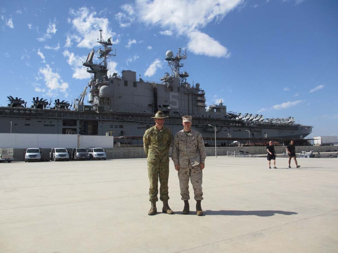 Major Benajmin Watson (left), assistant operations officer, 15th Marine Expeditionary Unit, stands with Lt. Col. Bill Wischmeyer, operations officer, 15th MEU, in front of USS Peleliu in Aqaba, Jordan. Watson is part of an exchange program enabling him to serve in a Marine Corps unit for two years. The intent of the exchange program is to help build maturity in Australia’s amphibious program by providing maritime operational planning experience to its officers. The 15th MEU is deployed as part of the Peleliu ARG as a U.S. Central Command theater reserve force, providing support for maritime security operations and theater security cooperation efforts in the U.S. 5th Fleet area of responsibility. (Courtesy Photo, Undated)


