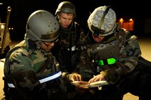 Airman 1st Class Roosevelt Cooper, left,  Airman Steven Schulze, middle, and Staff Sgt. Chana Lawlor, 8th Logistics Readiness Squadron, check the Airmen’s Manual for how to move a person with a leg fracture during exercise Beverly Midnight 13-2 at Kunsan Air Base, Republic of Korea, March 19, 2013. The scenario tested the 8th LRS’s ability to respond to and treat injured personnel following a ground attack. (U.S. Air Force photo by Senior Airman Marcus Morris/Released)