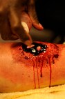 Tech. Sgt. Tremayne Glover, 8th Medical Operations Squadron moulage artist, sprays fake blood onto a simulated leg fracture during exercise Beverly Midnight 13-2 at Kunsan Air Base, Republic of Korea, March 19, 2013. Glover made the simulated wounds as realistic as possible to ensure personnel responded more accurately while treating them. (U.S. Air Force photo by Senior Airman Marcus Morris/Released)