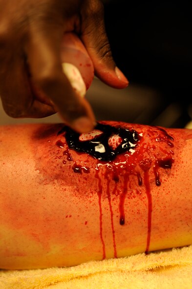 Tech. Sgt. Tremayne Glover, 8th Medical Operations Squadron moulage artist, sprays fake blood onto a simulated leg fracture during exercise Beverly Midnight 13-2 at Kunsan Air Base, Republic of Korea, March 19, 2013. Glover made the simulated wounds as realistic as possible to ensure personnel responded more accurately while treating them. (U.S. Air Force photo by Senior Airman Marcus Morris/Released)