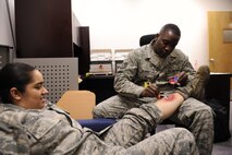 Tech. Sgt. Tremayne Glover, right, 8th Medical Operations Squadron moulage artist, creates a simulated leg fracture during exercise Beverly Midnight 13-2 at Kunsan Air Base, Republic of Korea, March19, 2013. Glover made the simulated wounds as realistic as possible to ensure personnel responded more accurately while treating them. (U.S. Air Force photo by Senior Airman Marcus Morris/Released)