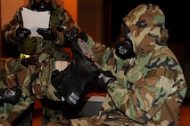 Senior Airman Stephen Shannon, 8th Civil Engineer Squadron, helps Staff Sgt. Hezekiah Barrett, 8th Medical Operations Squadron, remove contaminated Mission Oriented Protective Posture gear during exercise Beverly Midnight 13-2 at Kunsan Air Base, Republic of Korea, March 19, 2013. After finding contamination on his teammate, Shannon  alerted emergency personnel  and helped Barrett remove the gear. (U.S. Air Force photo by Senior Airman Marcus Morris/Released)