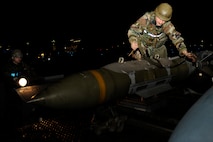 Staff Sgt. Gregory Harrison, right, 8th Aircraft Maintenance Squadron, straps down a bomb during exercise Beverly Midnight 13-2 at Kunsan Air Base, Republic of Korea, March 19, 2013. The Airmen prepared an F-16 Fighting Falcon for the first set of take-offs for the exercise, which assessed the readiness of the base.  (U.S. Air Force photo by Senior Airman Marcus Morris/Released)