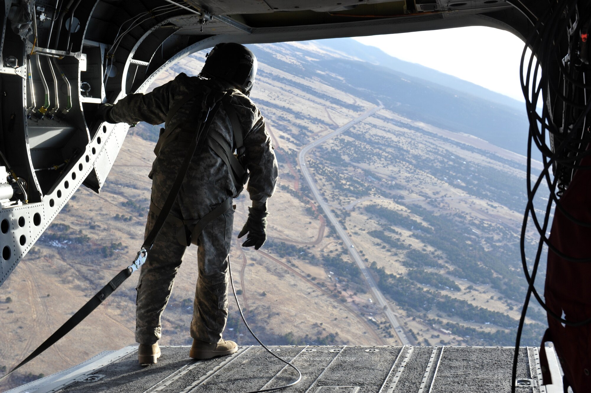 Staff Sgt. Edwin Thompson, Colorado Army National Guard Aviation Support Facility crew chief, examines the drop zone from a CH-47 Chinook March 6, 2013, at Fort Carson, Colo. With the assistance of the Aviation Support Facility members and assets, 10th Special Forces Group members parachuted from the Chinook as part of a training mission. (U.S. Air Force photo by Airman 1st Class Riley Johnson/Released)