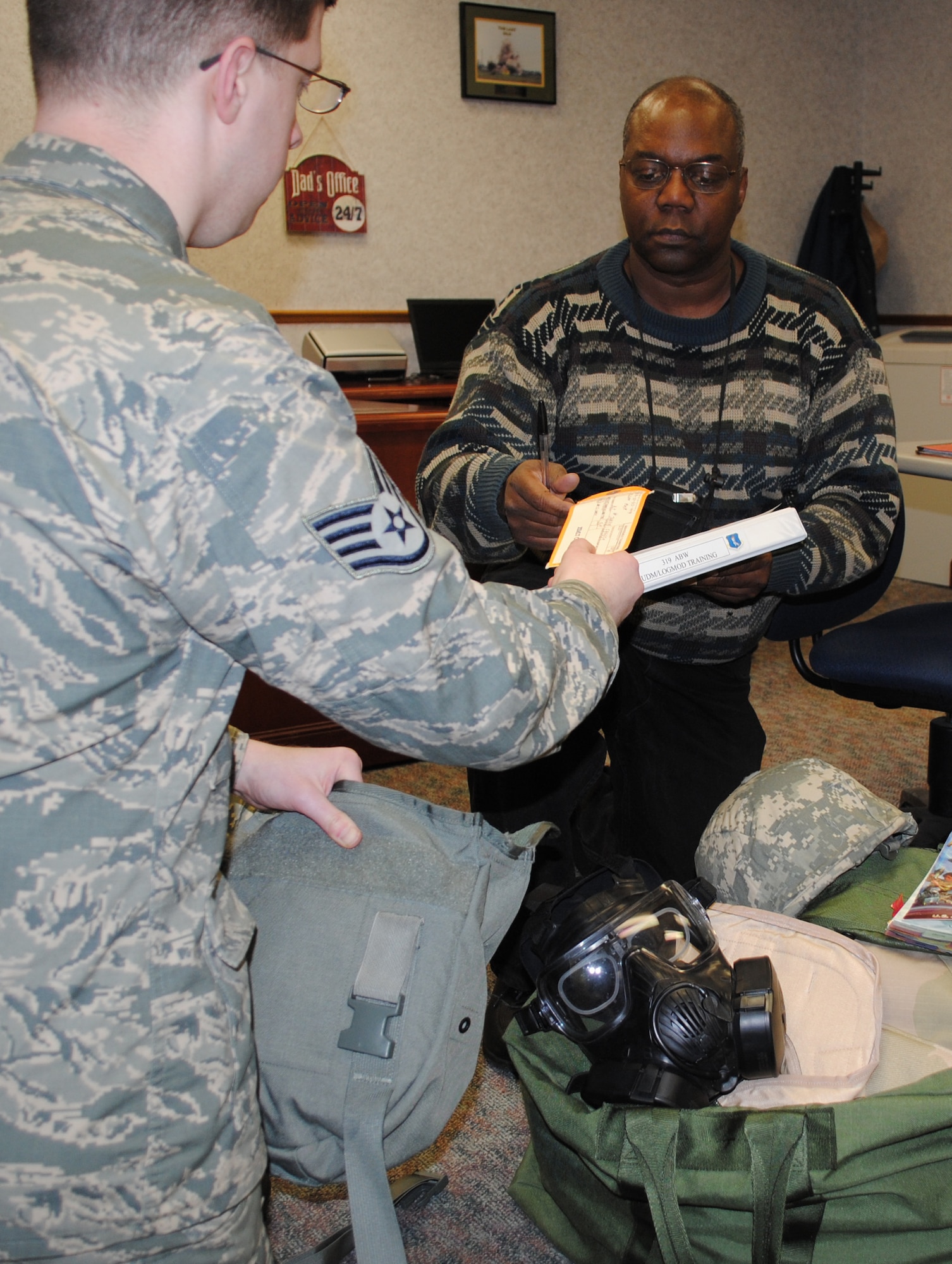 James Bolton, a unit deployment manager for the 319th Air Base Wing Staff Agencies, verifies the date on an Airman’s gas mask inspection card on March 15, 2013, at his office on Grand Forks Air Force Base, N.D. Before becoming a civil servant, Bolton retired as master sergeant after 25 years of service in the Air Force. (U.S. Air Force photo/Senior Airman Luis Loza Gutierrez)