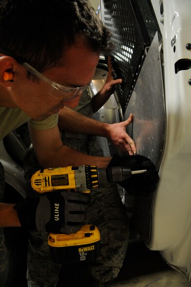 Airman 1st Class Cody Akers and Staff Sgt. Davis McClain, from of the 2nd Logistics Readiness Squadron Allied Trades section, drill paneling onto the door of a government owned vehicle on Barksdale Air Force Base, La., March 19. The allied trade shop's main responsibilities include tire repair and replacement and body work for Barksdale's fleet of vehicles ranging from fire trucks, maintenance and government owned vehicles. (U.S. Air Force photo/Airman 1st Class Andrew Moua)