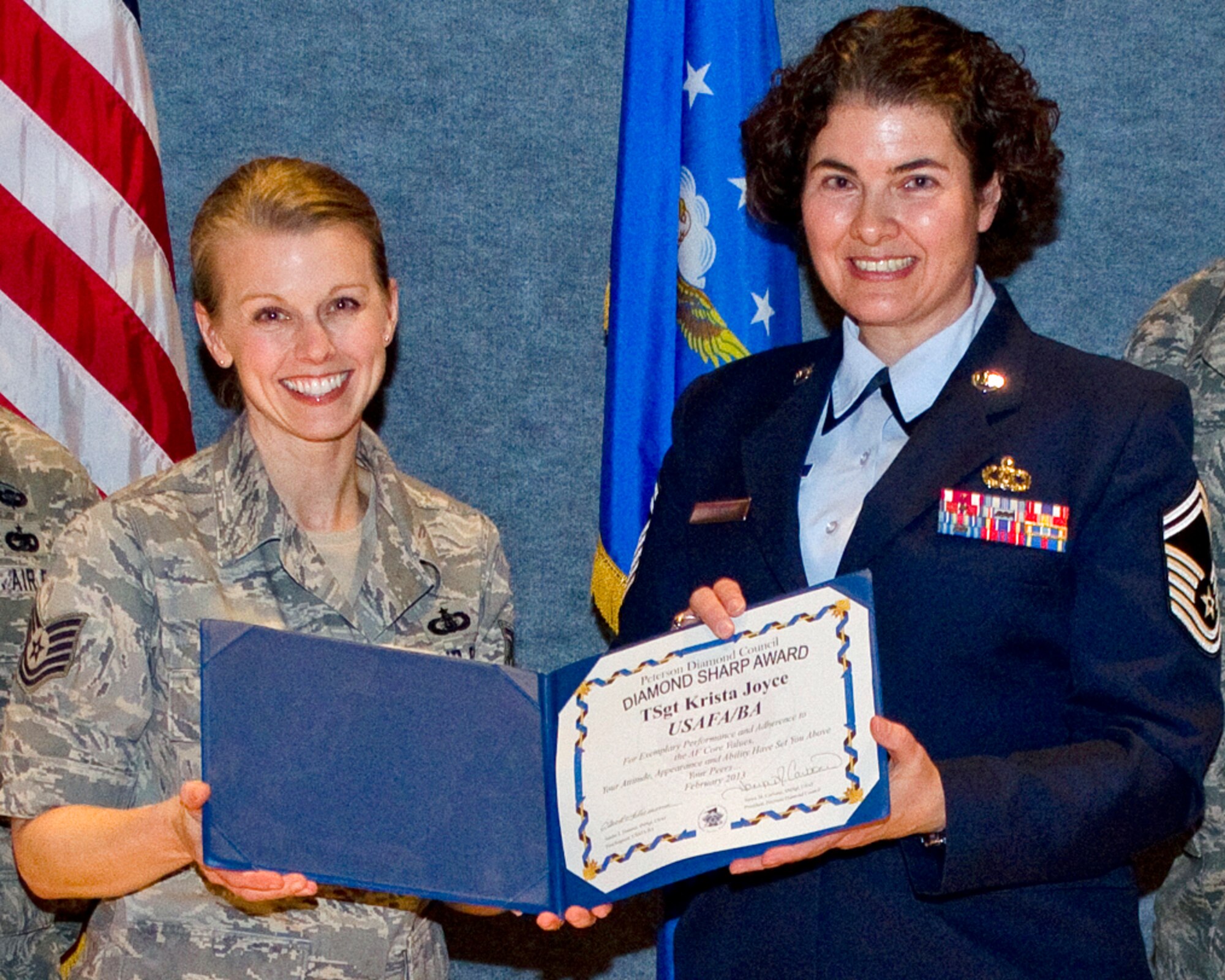 PETERSON AIR FORCE BASE, Colo. – Tech. Sgt. Krista Joyce (left), U.S. Air Force Academy Band vocalist, receives the Team Peterson First Sergeants Council Diamond Sharp Airman award from Senior Master Sgt. Sandra Tiemens, USAFA Band additional duty first sergeant. The award recognizes Airmen who go beyond their everyday tasks and demonstrate a high level of excellence, specifically in customer service and professional appearance. The Sharp Warrior Award is awarded each month in recognition of Team Petersons’ best. Any first sergeant or senior NCO serving as a first sergeant who observes outstanding performance may nominate someone for the award to the first sergeants council. (U.S. Air Force photo)