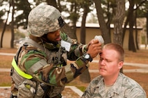 Staff Sgt. Eric Murphy, 8th Security Forces Squadron, treats the head wound of Staff Sgt. Michael O’Brien, 8th Fighter Wing role-player, during exercise Beverly Midnight 13-2 at Kunsan Air Base, Republic of Korea, March 19, 2013. The simulated injury adds a sense of realism to the training scenario. (U.S. Air Force photo by Staff Sgt. Jonathan Fowler/Released)