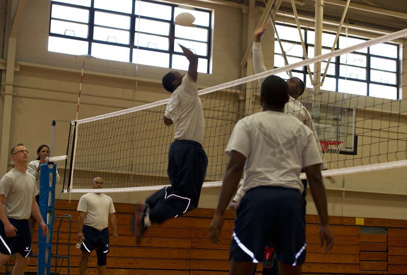 Airmen from the 628th Air Base Wing staff agencies jump to spike a volleyball during a match as part of a Wingman day competition March 14, 2013, at the Fitness Center on Joint Base Charleston, S.C. Wingman Day, a quarterly event, allows Airmen to take a break from their daily duties and come together to focus on various key topics that impact their personal and professional lives. (U.S. Air Force/Staff Sgt. Rasheen Douglas)
