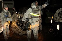 8th Security Forces Squadron members, Airman 1st Class Preston Mainz, left, carries concertina wire with Senior Airman Lawrence Threat, during exercise Beverly Midnight 13-2 at Kunsan Air Base, Republic of Korea, March 17, 2013. The c-wire was used to secure the perimeters and limit access of buildings. (U.S. Air Force photo by Senior Airman Marcus Morris/Released)