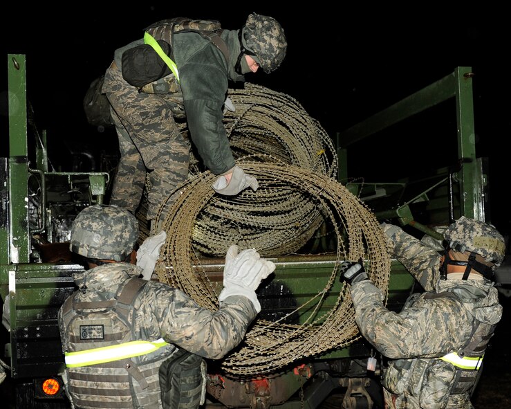 Staff Sgt. Jared Hay, bottom left, and Staff Sgt Jeffrey Self, bottom right, 8th Security Forces Squadron, load concertina wire onto a truck during exercise Beverly Midnight 13-2 at Kunsan Air Base, Republic of Korea, March 17, 2013. The c-wire was used to secure the perimeters and limit access of buildings. (U.S. Air Force photo by Senior Airman Marcus Morris/Released)