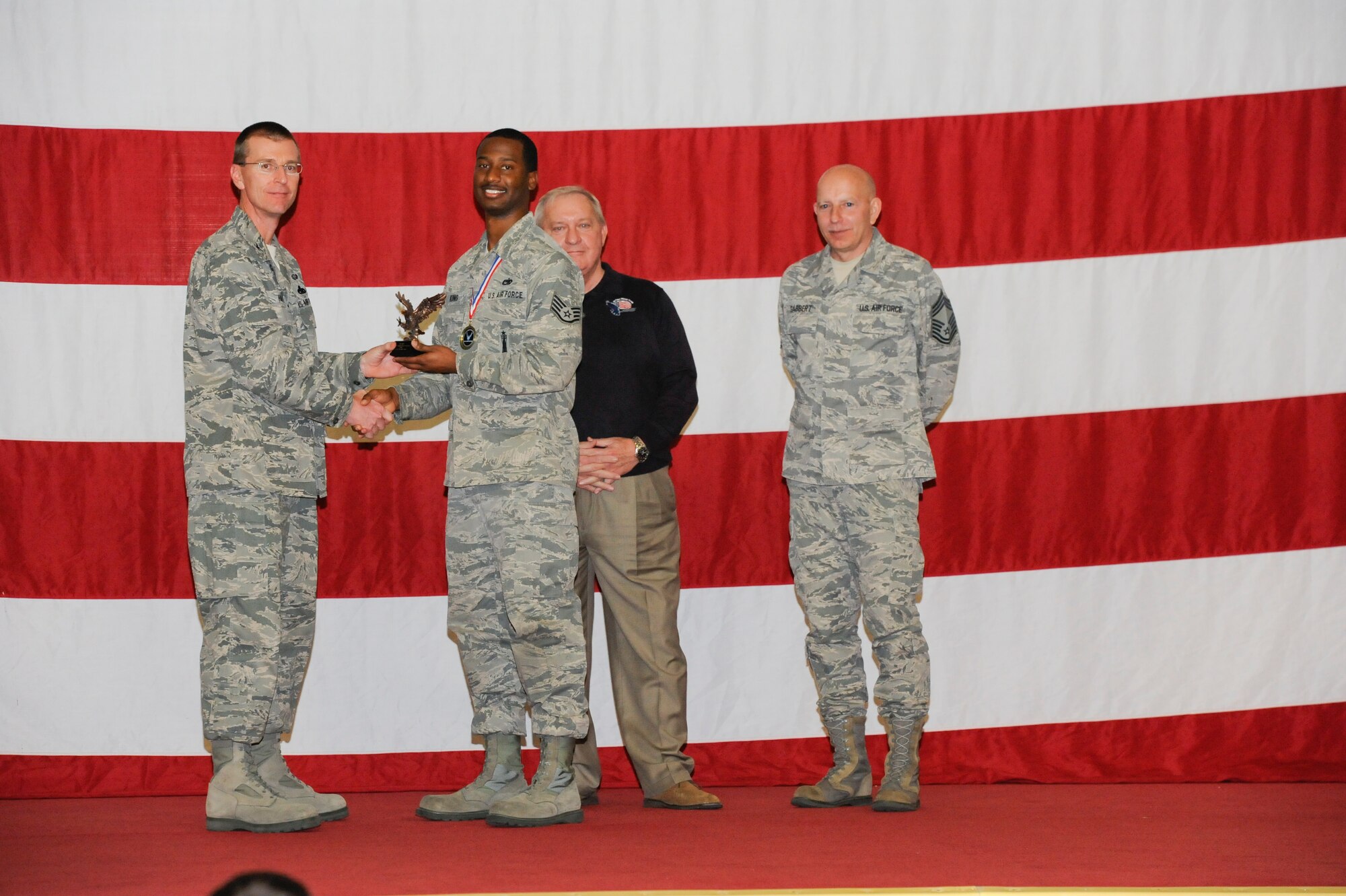 Staff Sgt. Daniel King earns the Weapons Jammer Driver of the Year Award during the 2012 Maintenance Professionals of the Year ceremony March 15 from Col. Curtis Hafer, 325th Maintenance Group commander, retired Chief Master Sgt. of the Air Force James Binnicker and Chief Master Sgt. Terry Gabbert, 325th Maintenance Group superintendent. (U.S Air Force photo by Chris Cokeing)