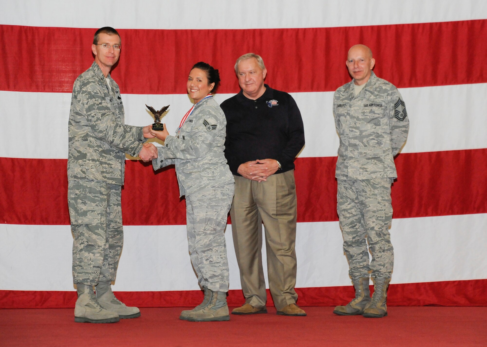 Senior Airman Ashley Osgood earns the ACC Outstanding Munitions Technician Award during the 2012 Maintenance Professionals of the Year ceremony March 15 from Col. Curtis Hafer, 325th Maintenance Group commander, retired Chief Master Sgt. of the Air Force James Binnicker and Chief Master Sgt. Terry Gabbert, 325th Maintenance Group superintendent. (U.S Air Force photo by Chris Cokeing)