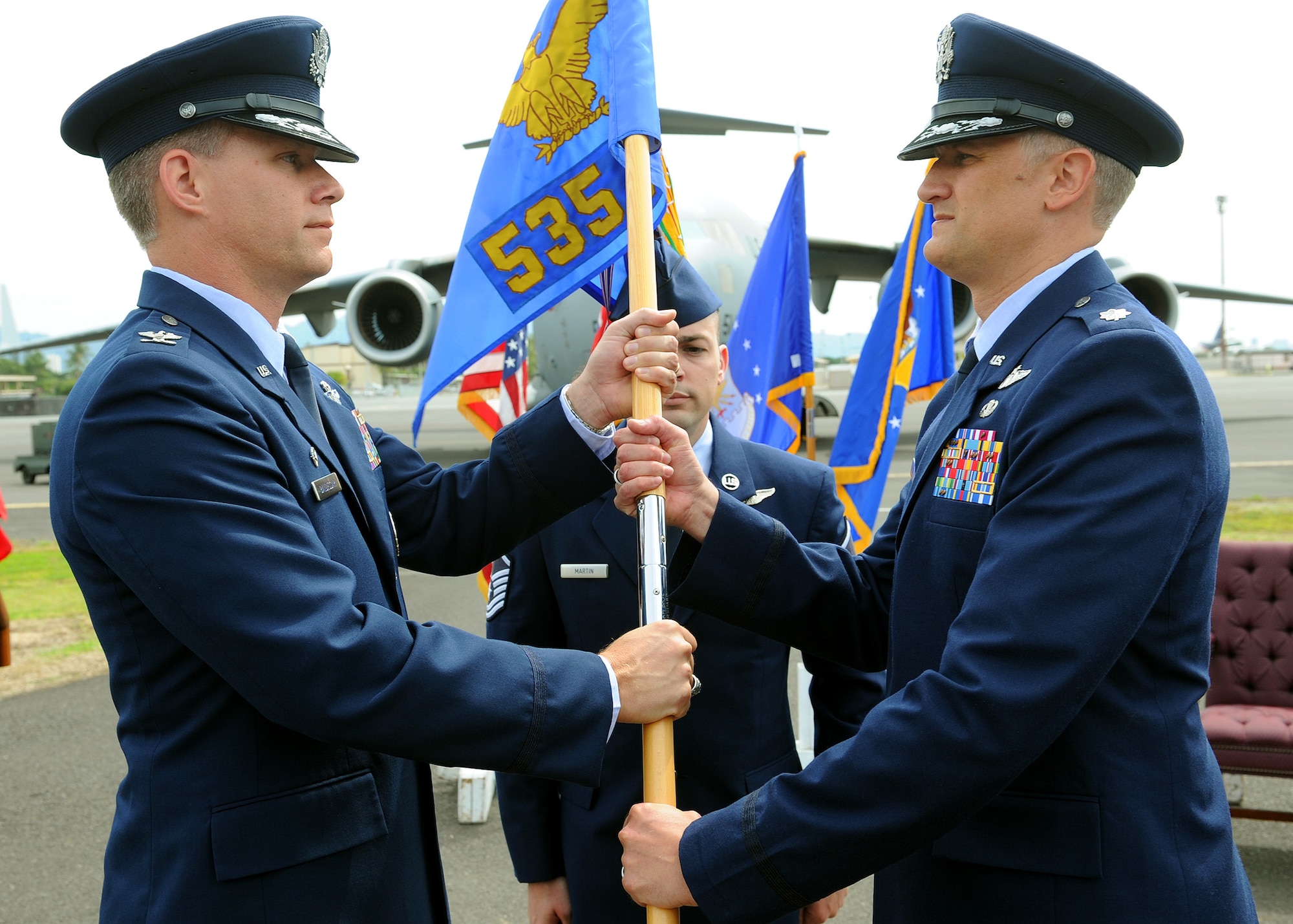 Col. Dan Baldessari, 15th Operations Group commander, presents the squadron guidon to Lt. Col. Gregg S. Johnson at the 535th Airlift Squadron change of command ceremony as Master Sgt. Ryan Martin 535th AS first sergeant, looks on near the flightline at Joint Base Pearl Harbor-Hickam, Hawaii, March 15, 2013. (U.S. Air Force photo/Tech. Sgt. Jerome S. Tayborn)