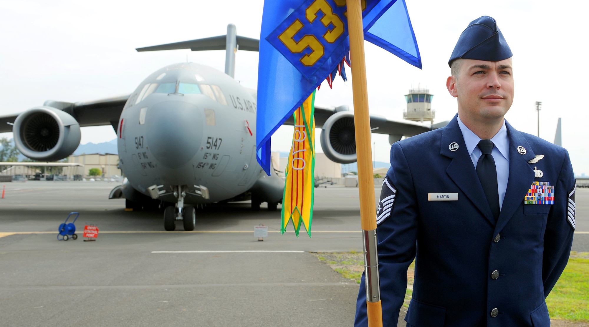 Master Sgt. Ryan Martin, 535th Airlift Squadron first sergeant, stands at parade rest while holding the unit’s guidon in front of a C-17 Globemaster III, during the squadron’s change of command ceremony, near the flightline at Joint Base Pearl Harbor-Hickam, Hawaii, March 15, 2013.  The 535th AS has provided humanitarian assistance and disaster relief to China, Indonesia, American Samoa, Haiti, and Japan. (U.S. Air Force photo/Tech. Sgt. Jerome S. Tayborn)