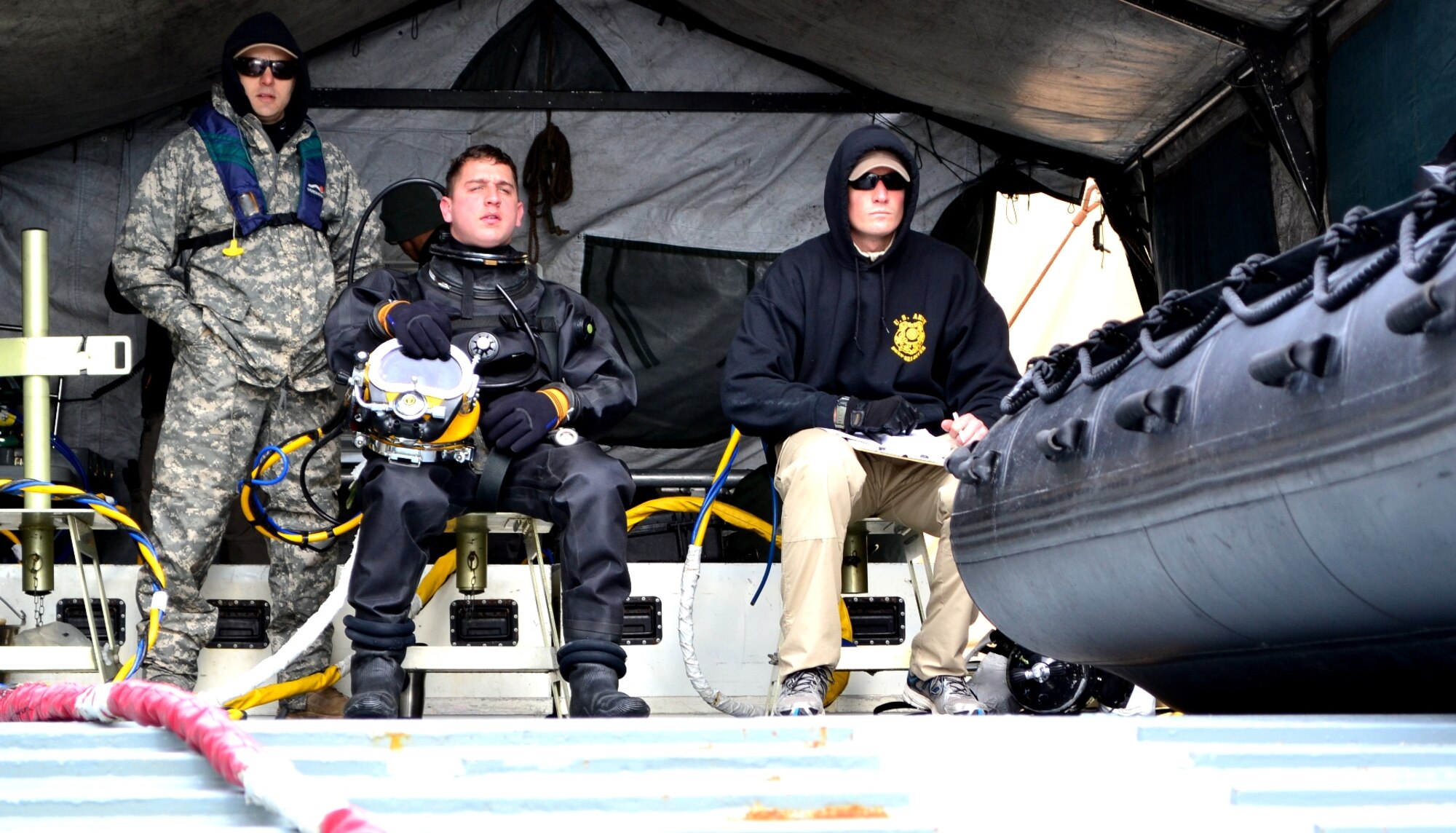 U.S. Army Spc. Jacob Feyers, center, assigned to the 511th Dive Detachment, Special Troops Battalion, 7th Sustainment Brigade, sits next to Spc. Thomas Dougherty and waits patiently as his lead diver is below water during a training exercise off the Cheatham Annex Naval Station, Va. shore March 6, 2013. The team was evaluated on how successfully they could operate when normal dive operations go awry.  (U.S. Army photo by Sgt. Edwin Rodriguez/Released)