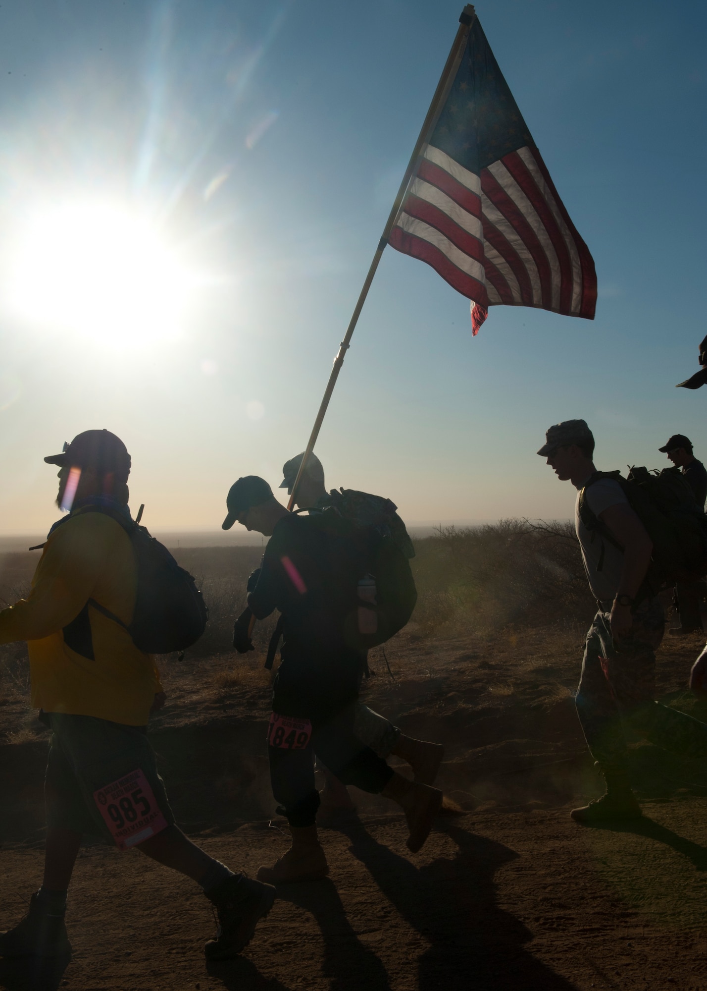 Participants in the 24th annual Bataan Memorial Death March carry an American flag after the start of the event at White Sands Missile Range, N.M., March 17. Over 5,800 people came to honor more than 76,000 Prisoners Of War/Missing In Action from Bataan and Corregidor during World War ll. The 26.2-mile course starts on WSMR, enters hilly terrain and finishes through sandy desert trails, with elevation ranging from 4,100-5,300 feet. This year 13 veterans from World War ll attended the event. (U.S. Air Force photo by Airman Leah Murray/Released)