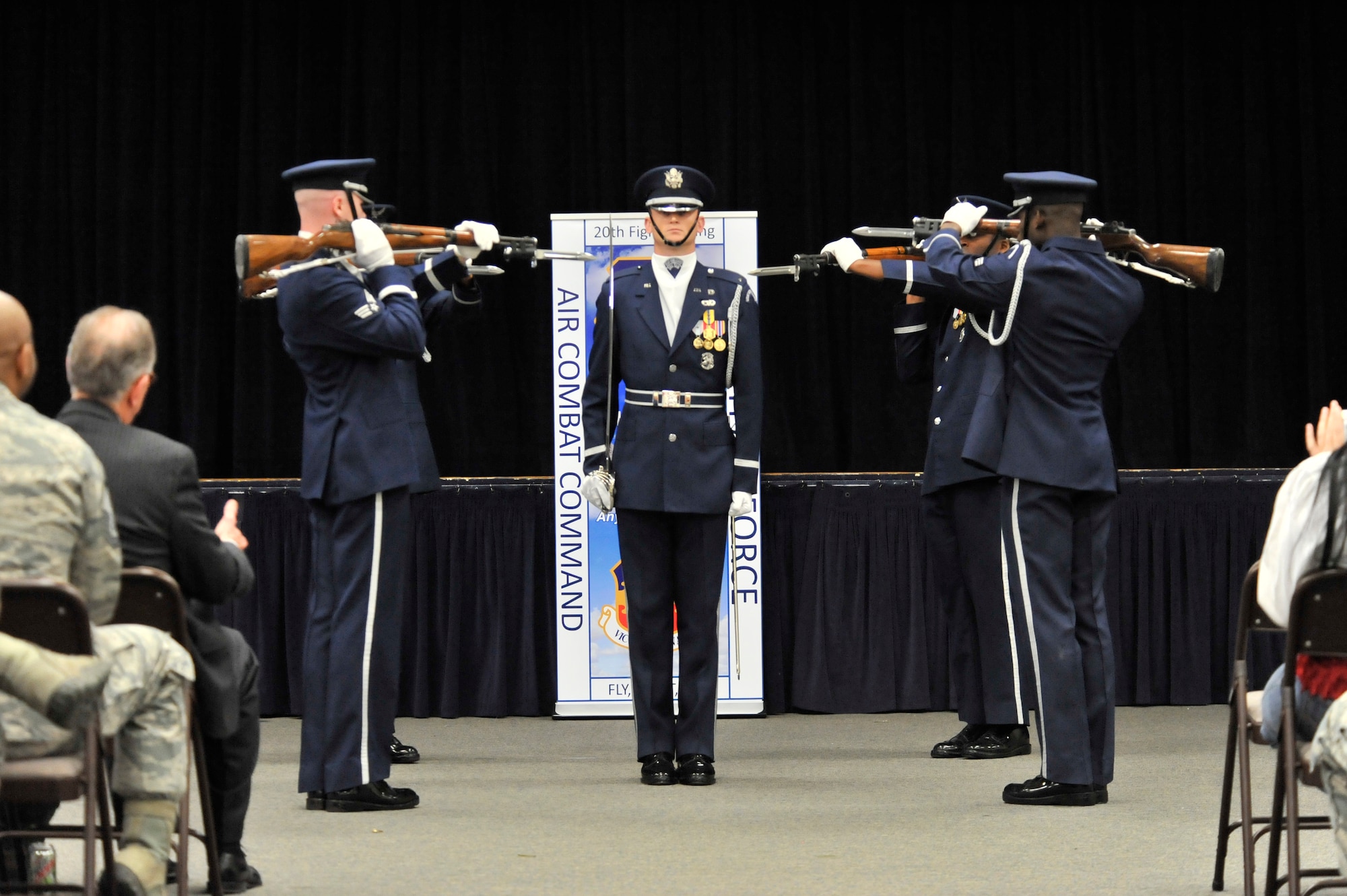 U.S. Air Force 1st Lt. Michael Lemorie (center), USAF Honor Guard Drill Team commander, stands at attention during a performance while honor guard team members perform movements around him, Shaw Air Force Base Community Activity Center, S.C., March 15, 2013. The honor guard visited Shaw in an effort to recruit new members. (U.S. Air Force photo by Senior Airman Amber E. N. Jacobs/Released)