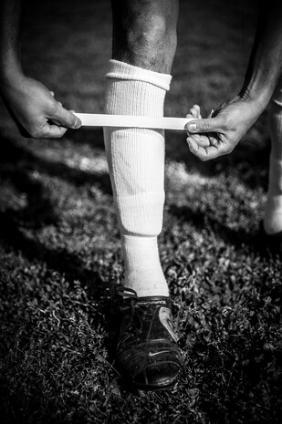 A member of the 437th Aircraft Maintenance Squadron intramural soccer team places tape around his shin guards before the start of a game against the 437th Aerial Port Squadron team March 14, 2013, at the Joint Base Charleston – Air Base soccer fields. The 437th AMXS soccer team squeaked by the 437th APS soccer team in a 4 – 2 shootout win in Joint Base Charleston’s 2013 intramural soccer season opener. (U.S. Air Force photo/ Senior Airman Dennis Sloan)