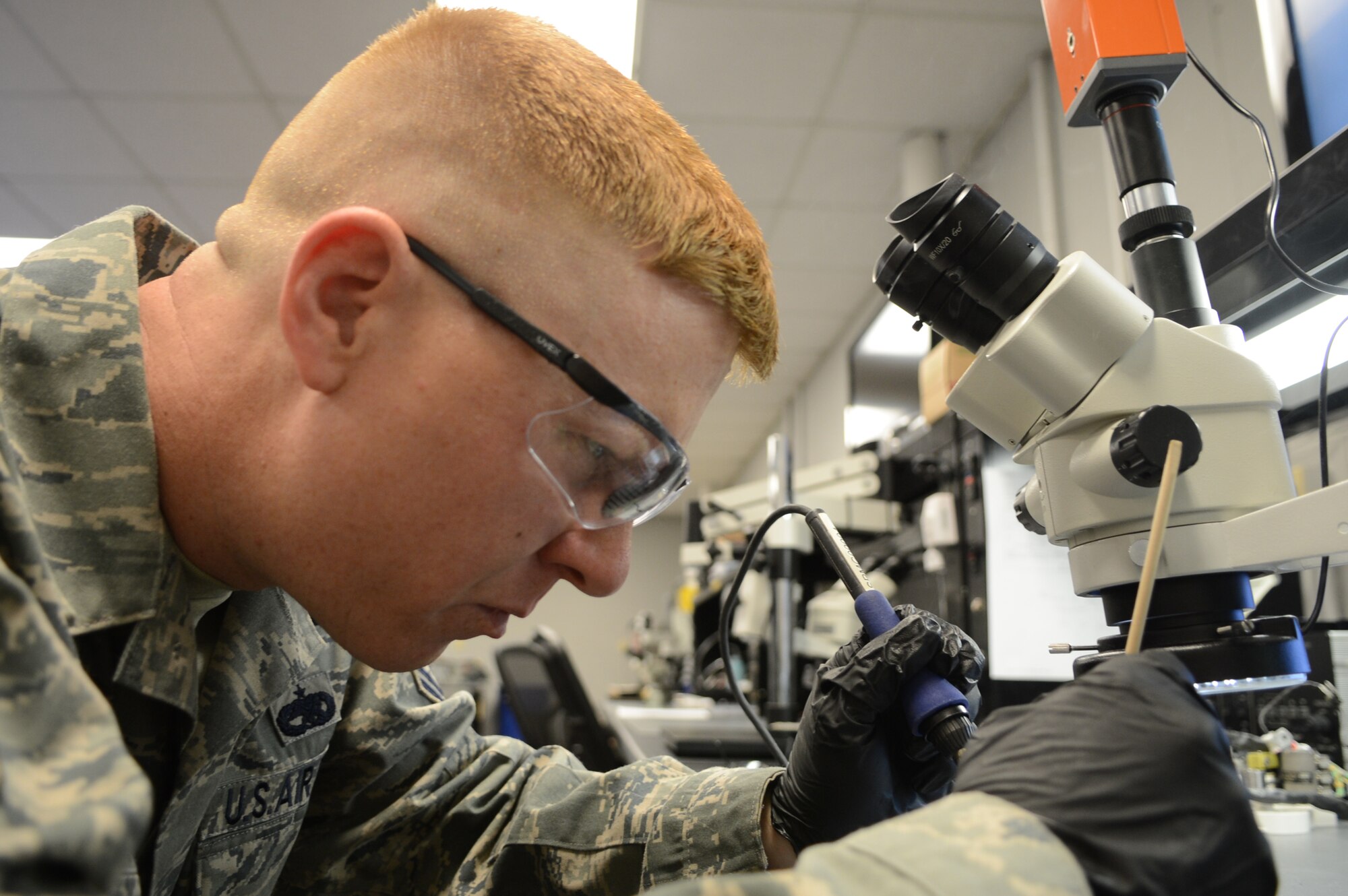 U.S. Air Force Tech. Sgt. Caleb Nicholas, 20th Maintenance Group Air Force Enhancement Program manager, looks under a microscope as he fixes a signal light at Shaw Air Force Base, S.C., March 14, 2013. AFREP is a program that revolves around finding parts that are being thrown away and finding ways to repair them. (U.S. Air Force photo by Airman 1st Class Nicole Sikorski/Released) 
