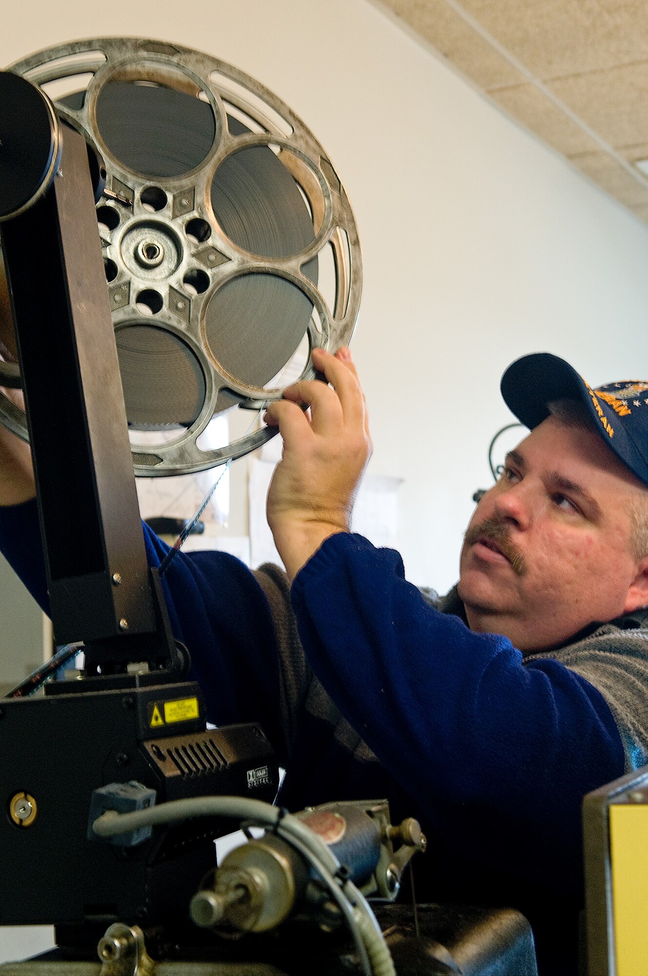 Kevin Arnold, Dover Air Force Base theater supervisor, loads film onto a Simplex 35mm projector March 15, 2013, at Dover Air Force Base, Del. The Simplex machines will be replaced as the theater undergoes digital upgrades March 18-20. (U.S. Air Force photo/Airman 1st Class Kathryn Stilwell)