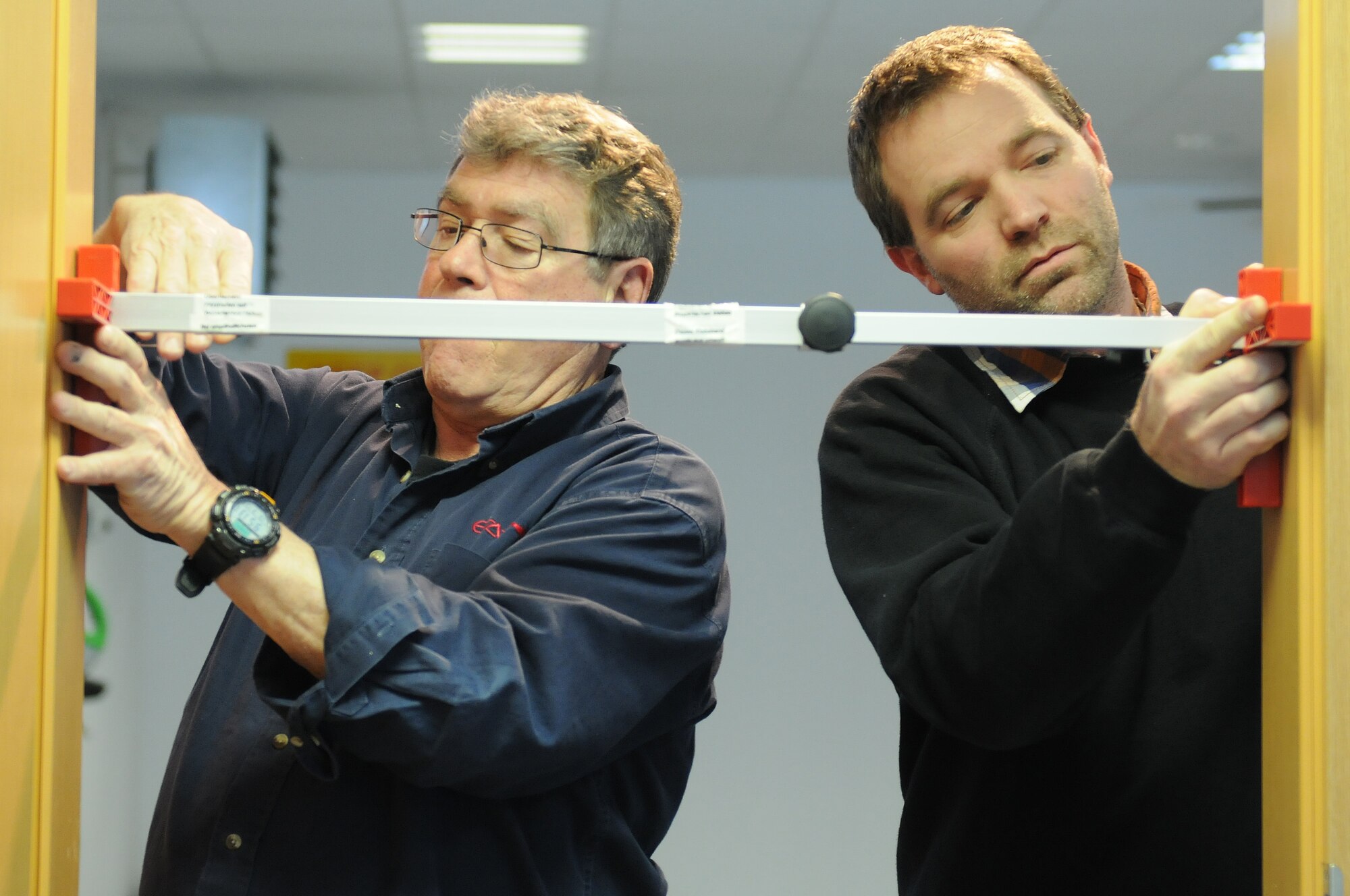 Russell Scaroni, civil engineer self-help store structure planner, instructs Marc Fischer, CE self-help store customer service technician, with installing a door at the CE self-help store on Ramstein Air Base, Germany, March 15, 2013. The CE self-help store provides the base with their entire repair and clean up needs. (U.S. Air Force photo/Airman 1st Class Holly Cook)