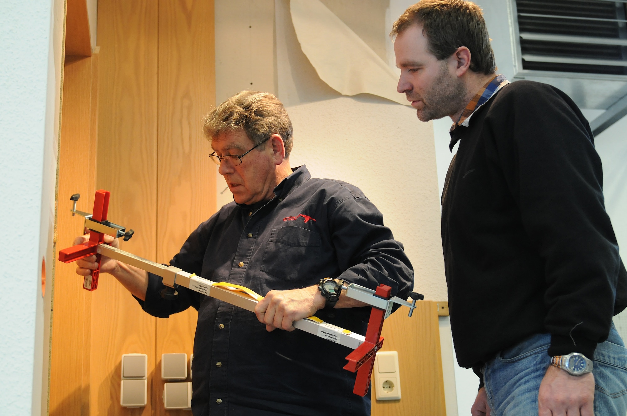 Russell Scaroni, civil engineer self-help store structure planner, instructs Marc Fischer, CE self-help store customer service technician, with installing a door at the CE self-help store on Ramstein Air Base, Germany, March 15, 2013. The CE self-help store provides the base with their entire repair and clean up needs. (U.S. Air Force photo/Airman 1st Class Holly Cook)