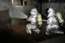 Kil Su Son, left, and Chae Ung Yang, 8th Civil Engineer Squadron, spray water at a fire during exercise Beverly Midnight 13-2 at Kunsan Air Base, Republic of Korea, Mar. 18, 2013. The fire was part of a training scenario designed to evaluate the capabilities of the firefighters. (U.S. Air Force photo by Senior Airman Marcus Morris/Released)
