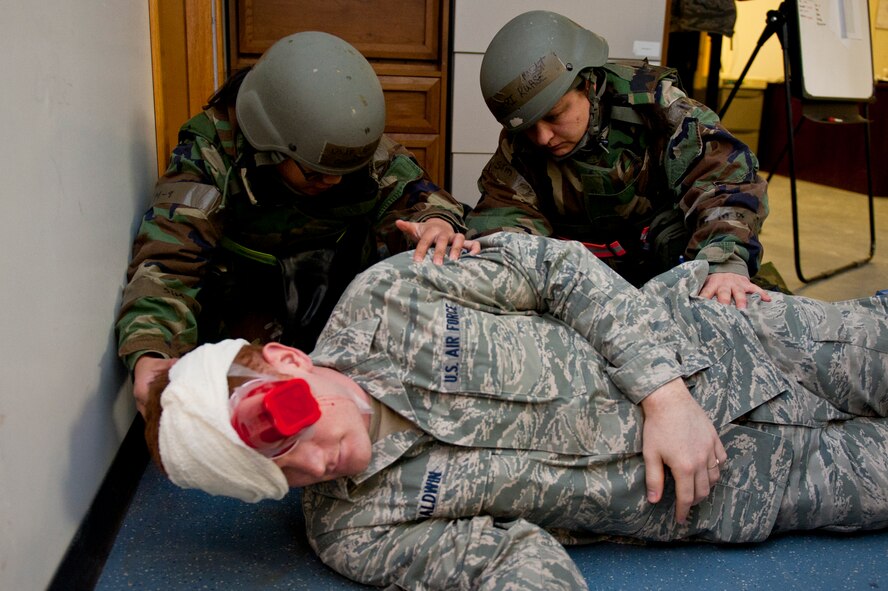 Senior Airman Carrie Oria, 8th Logistics Readiness Squadron, left, and Master Sgt. Torri Kuhse, 8th Force Support Squadron, turn over SrA Kipp Baldwin, 8th Fighter Wing role player, while checking for additional wounds following a simulated mortar attack at Kunsan Air Base, Republic of Korea, March 19, 2013. The attack was a training scenario for Beverly Midnight 13-2 and tested the Wolf Pack’s readiness. (U.S. Air Force photo by Staff Sgt. Jonathan Fowler/Released)