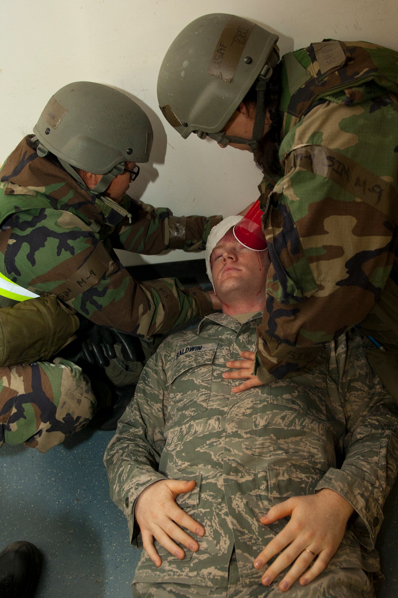 Senior Airman Carrie Oria, 8th Logistics Readiness Squadron, left, and Master Sgt. Torri Kuhse, 8th Force Support Squadron tend to the wounds of Senior Airman Kipp Baldwin, 8th Fighter Wing role player, following a simulated mortar attack at Kunsan Air Base, Republic of Korea, March 19, 2013. The attack was a training scenario for Beverly Midnight 13-2 and allowed Oria and Kuhse to practice their Self-Aid and Buddy Care procedures. (U.S. Air Force photo by Staff Sgt. Jonathan Fowler/Released)