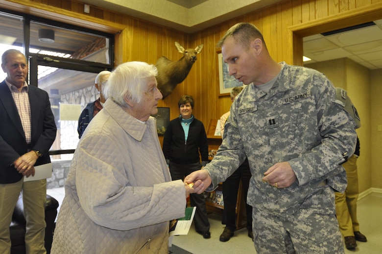 Joyce Halcomb, wife of deceased Park Ranger Wallace Halcomb, is honored with flowers and a district coin presented by U.S. Army Corps of Engineers Capt. Allen Stansbury, Wolf Creek Dam Foundation Remediation Project officer. District personnel at Lake Cumberland unveiled an honorary display wall today to commemorate the service of park rangers during a ceremony at the Lake Cumberland Visitor's Center March 13, 2013. 