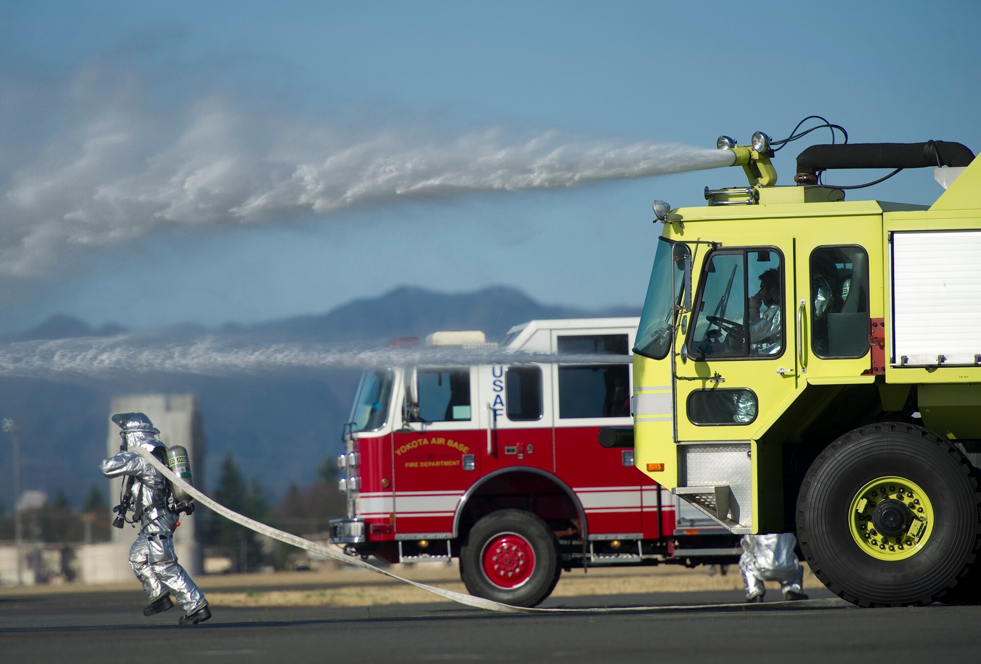 YOKOTA AIR BASE, Japan -- A firefighter from the 374th Civil Engineer Squadron runs with a hose to a simulated burning aircraft during an emergency management exercise at Yokota Air Base, Japan, Mar. 21, 2013. The EME was held in an effort to strengthen Yokota’s bilateral capability with local Japanese response teams. (U.S. Air Force photo by SSgt Chad C. Strohmeyer)