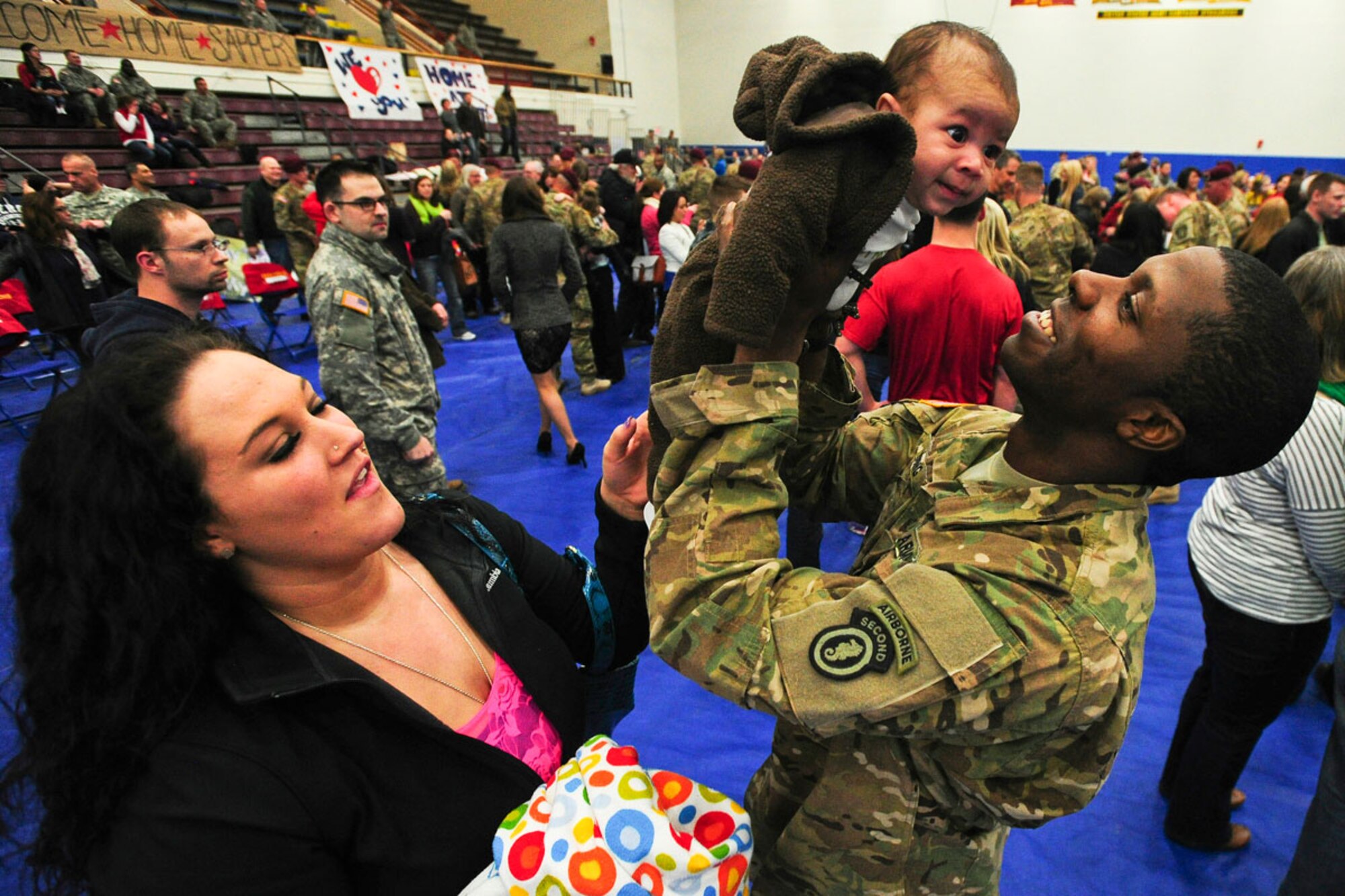 Sgt. Tony Young, a native of Los Angeles, holds up his son, Jayce, as his wife, Jaime Young, watches the two meet for the fi rst time during the 23rd Engineer Company’s redeployment ceremony at Buckner Physical Fitness Center on JBER March 14. Nearly 100 U.S. Army Alaska Soldiers returned home to JBER March 14 from a nine-month deployment to the southern provinces of Afghanistan in support of Operation Enduring Freedom. The Soldiers are assigned to the 23rd Engineer Company, part of the 6th Engineer Battalion, 2nd Engineer Brigade, home-based at JBER. During the Sappers’ deployment, the Soldiers performed dangerous route-clearance missions to remove improvised explosive devices along often-used roads to reduce the dangers of travel. The unit was featured in the National Geographic Channel’s “Bomb Hunters: Afghanistan,” and three-part Discovery Channel documentary “Heroes of Hell’s Highway.” (U.S. Air Force photos/Justin Connaher) 