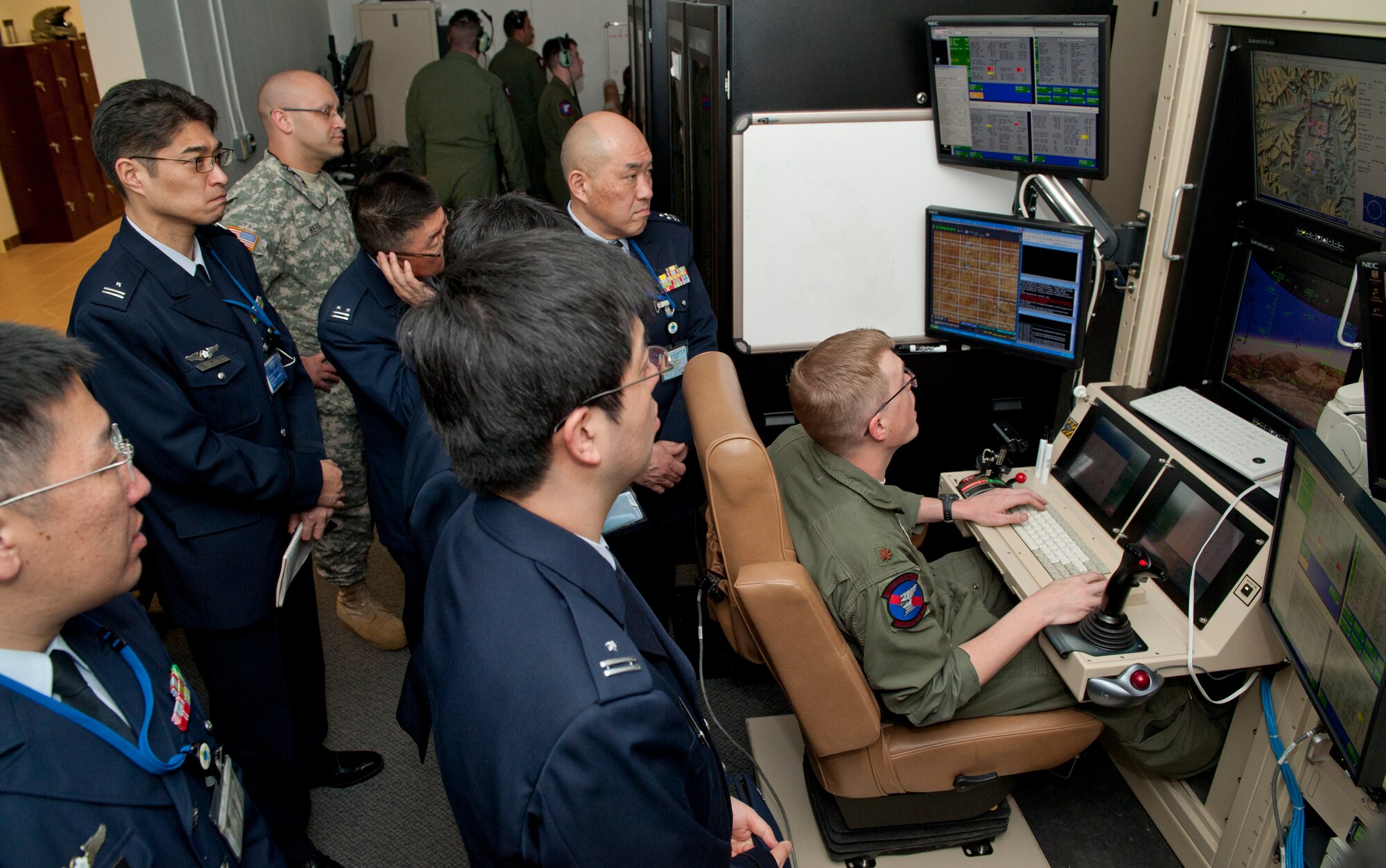 Major Michael [last name withheld due to operations security constraints], 9th Attack Squadron, flight commander, demonstrates flying an MQ-9 Reaper in a flight simulator to members of the Japan Air Self Defense Force at Holloman Air Force Base, N.M., March 19. The Remotely Piloted Aircraft program was briefed to the members of the Japan Air Self Defense Force. Their visit to Holloman AFB was part of an effort to bolster Japanese intelligence, surveillance and reconnaissance capability. (U.S. Air Force photo by Airman 1st Class Colin Cates/Released) 