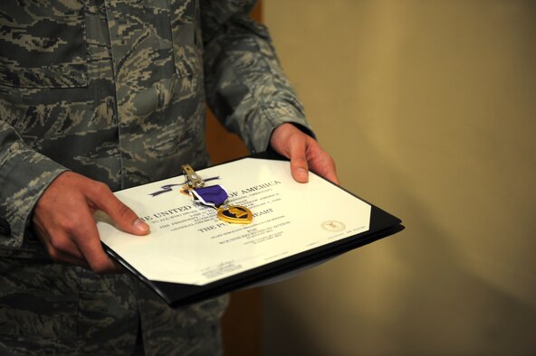 U.S. Air Force Senior Airman Logan Miller, 824th Base Defense Squadron, holds a Purple Heart Medal before it was given to Staff Sgt. Melissa Gschwend, 820th Base Defense Group standards and evaluation NCO, at Moody Air Force Base, Ga., March 15, 2013. Gschwend received the Purple Heart for her actions during a deployment. (U.S. Air Force photo by Airman 1st Class Olivia Bumpers/Released)