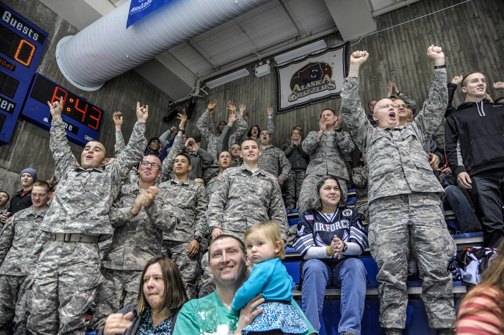 U.S. Air Force and U.S. Army service members celebrate a goal scored by the Fairbanks Ice Dogs at the Big Dipper Ice Arena Mar. 14, 2013, Fairbanks, Alaska.   Local businesses showed their military appreciation by purchasing tickets to the game for military members and their family members.  (U.S. Air Force Photo/Airman 1st Class Peter Reft)
