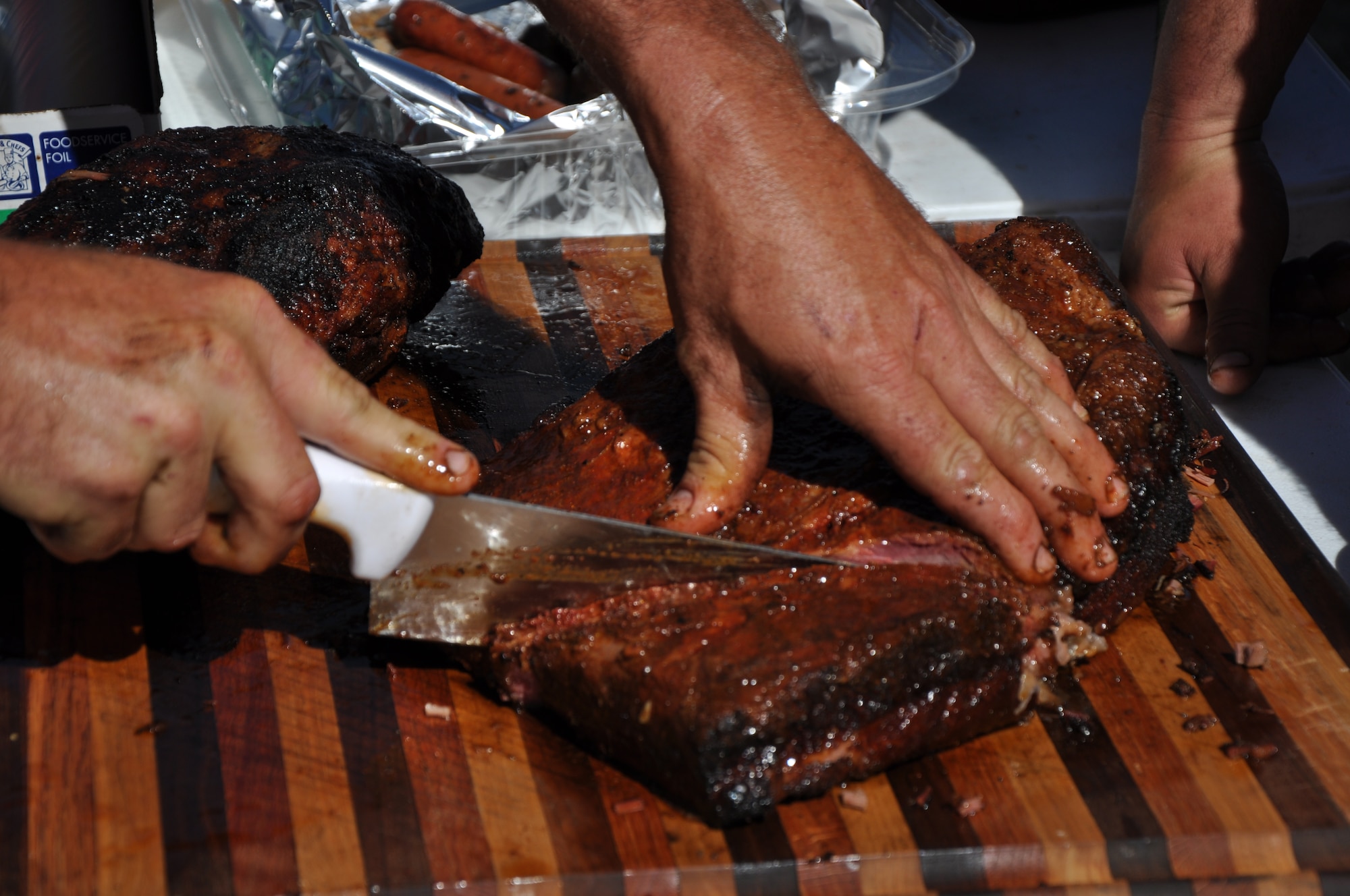 SAN ANGELO, Texas – Jace Watson, brisket cook-off competitor, cuts his brisket before the turn-in time for the third Annual Basewide Brisket Cook-Off at the Goodfellow Recreation Camp here March 16. Watson and his team, West Texas BBQ, turned in two different briskets for the competition. (U.S. Air Force photo/ Airman 1st Class Joshua Edwards)