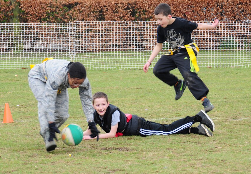 Tech. Sgt. Ashley Tyler, 100th Security Forces Squadron standardization evaluator from Baton Rouge, La., steals the ball from the opposing red team as she attempts to take it back to the yellow team’s side to score a point, during a game of flag football March 15, 2013, at the primary school in Beck Row, England. Airmen from the 100th SFS made an obstacle course and played flag football and soccer with children to encourage teamwork. (U.S. Air Force photos by Karen Abeyasekere/Released)