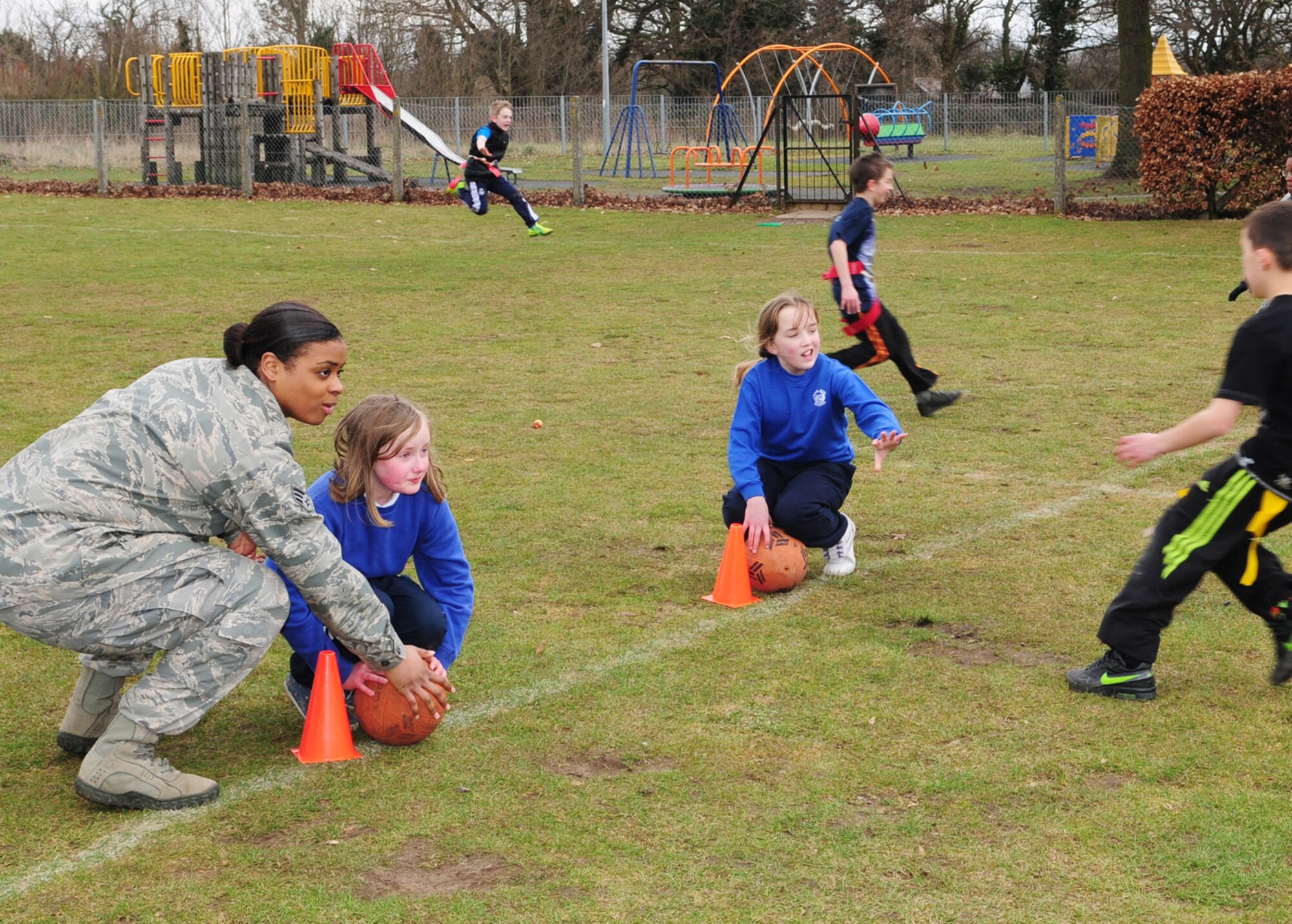 Left, Senior Airman Lauren Ortega, from New York City, 100th Security Forces Squadron standardization evaluator, plays flag football with children from Beck Row Primary School March 15, 2013, at Beck Row, England. The 100th SFS Defenders set up activities for the children to have fun and instill teamwork. (U.S. Air Force photo by Karen Abeyasekere/Released)