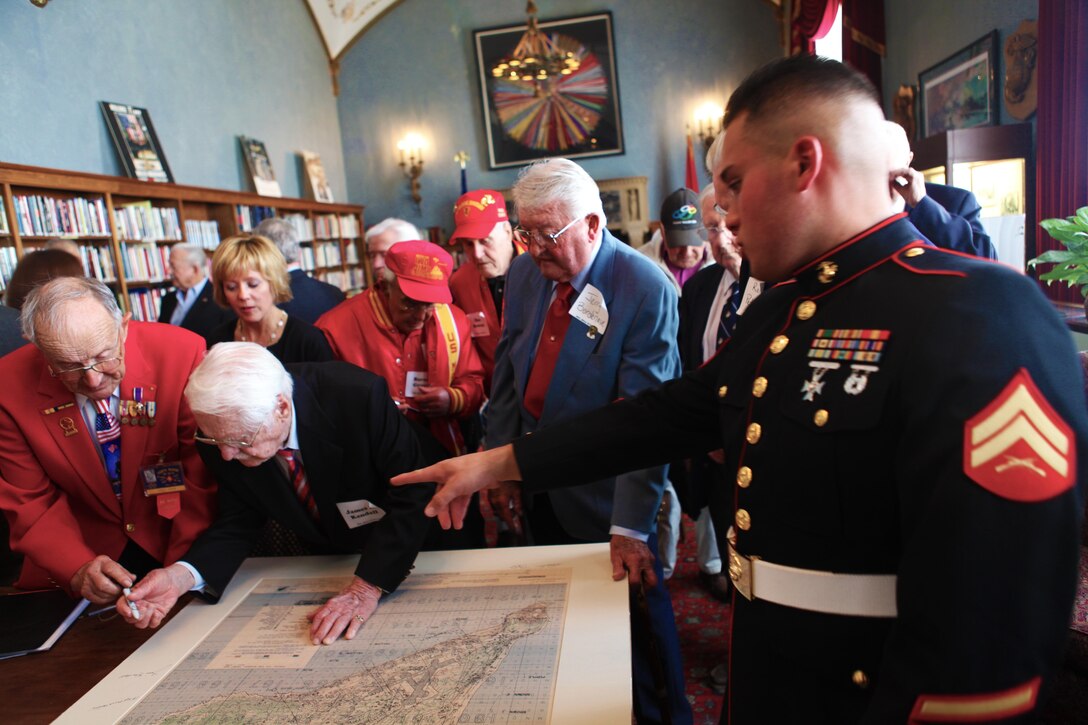 Cpl. Cesar W. Rivero shows veterans where to sign a copy of an Iwo Jima map at the Marines' Memorial Club and Hotel library in San Francisco March 13, 2013. Rivero,25, an administrative specialist assigned to Headquarters Company,23rd Marine Regiment, was there to assist with the proceedings at the 68th Anniversary of the Battle of Iwo Jima with a luncheon ceremony. The event was also an opportunity to accentuate the connection between the WWII-era 4th Marine Division with today's 4th Marine Division and Marine Forces Reserve. More than 100 veterans, modern Marines and guests were in attendance. 