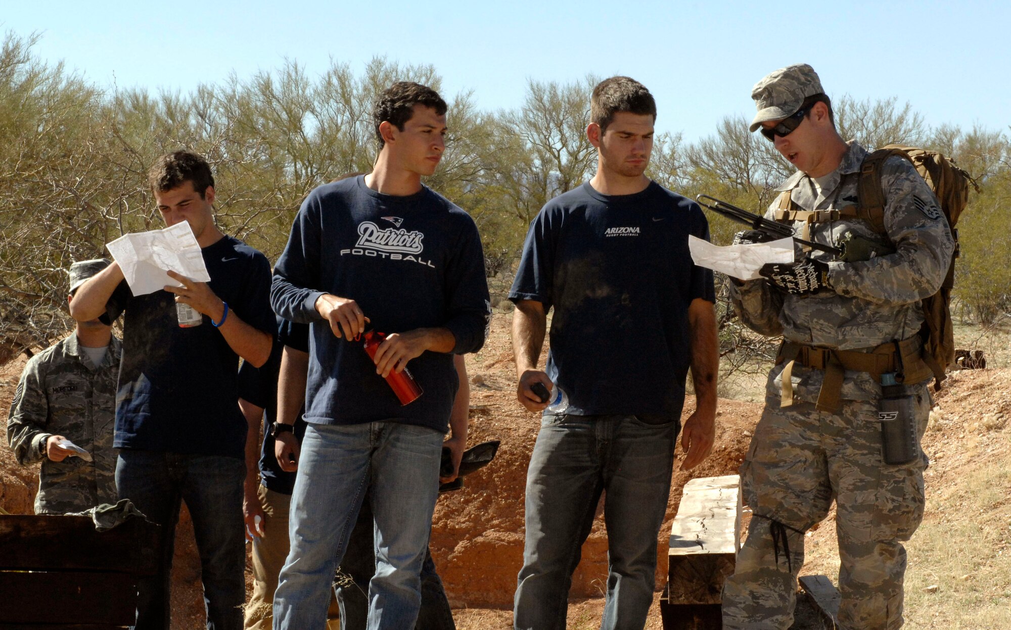 U.S. Air Force Staff Sgt. Josh Emerick, 55th Rescue Squadron, assists members of the University of Arizona rugby team with reading a map during a mock deployment hosted by the 55th RQS at Davis-Monthan Air Force Base, Ariz., March 16, 2013. For the mock deployment, the UofA rugby team was bused to a campsite behind the small arms range where they were split into groups and assigned to members of the 55th RQS, who acted as their team mentors. (U.S. Air Force photo by Senior Airman Saphfire Cook/Released)