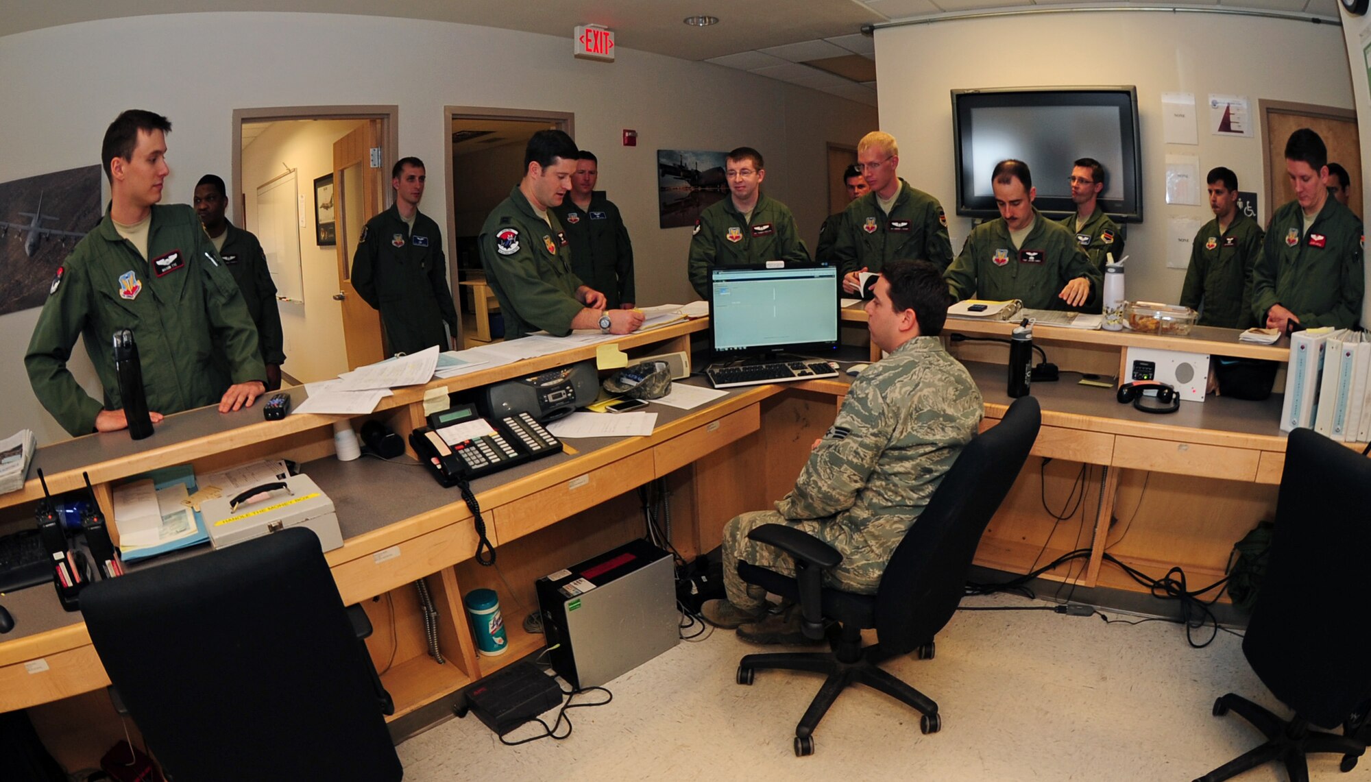 Members of the 43rd Electronic Combat Squadron gather for a pre-flight briefing at the operations desk at Davis-Monthan Air Force Base, Ariz., March 20, 2013. During pre-flight briefings, aircrew is given information about their flight. (U.S. Air Force photo by Senior Airman Camilla Griffin/Released)