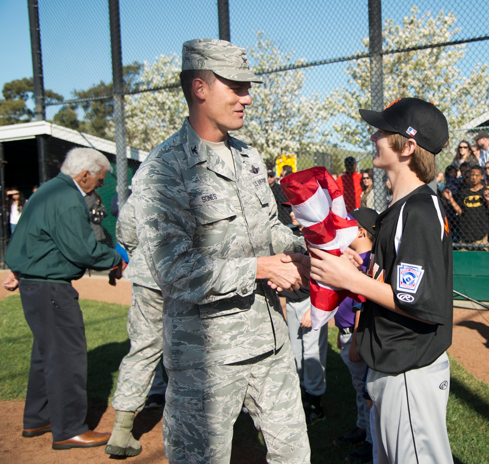 Col. Dwight Sones, 60th Air Mobility Wing commander, greets players from various Little League teams after presenting them with their new American flag. The original flag and equipment shed were burnt after vandalizes set them on fire. (U.S. Air Force photo/Airman 1st Class Nicole Leidholm)