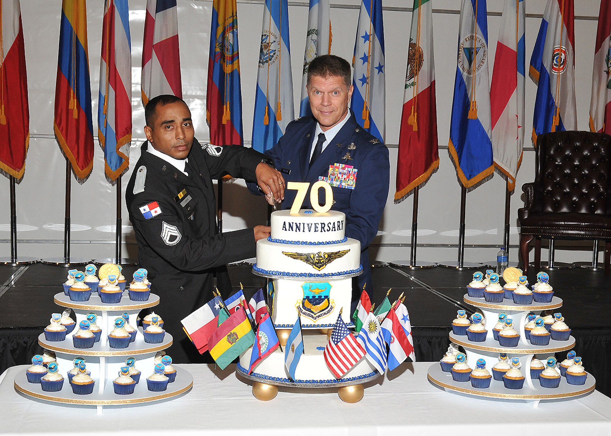 Sgt. Arnold Arias, left, a member of the Panamanian national police and U.S. Air Force Col. Marc Stratton, commandant, Inter- American Air Forces Academy, slice a cake during the Academy's 70th anniversary celebration at the IAAFA Airfield Training Complex, Joint Base San Antonio-Lackland. (U.S. Air Force photo by Alan Boedeker/Released)