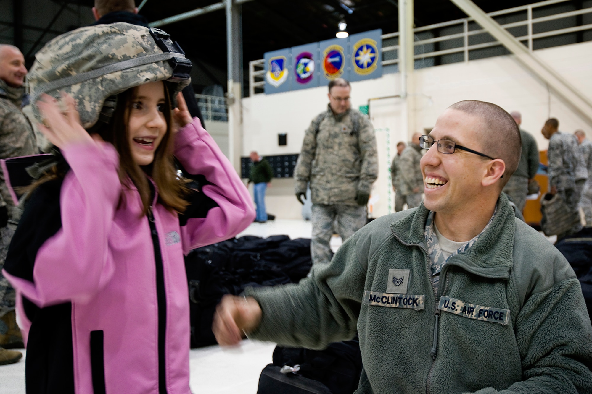 GRISSOM AIR RESERVE BASE, Ind. -- Staff Sgt. Michael McClintock, 434th Security Forces Squadron fire team, helps his daughter, Mackenzie, try on his helmet after returning from a recent deployment to the Transit Center at Manas, Kyrgyzstan, March 6. McClintock and 20 other security forces Airmen deployed for six months to provide security for the base. (U.S. Air Force photo/Senior Master Sgt. Scott Fleek)
