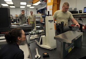 Jamaica Neussendorfer, 366th Component Maintenance Squadron contractor, and Staff Sgt. Len Carter, 366th CMS Test Measurement and Diagnostic Equipment quality assurance evaluator, work together to make adjustments on a standard alignment fixture, March 14, 2013, at Mountain Home Air Force Base, Idaho.  If the TMDE flight fails an inspection and loses certification, all the equipment would then have to be shipped to another location to be calibrated. (U.S. Air Force photo/Senior Airman Heather Hayward)
